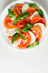 Close-up photo of caprese salad with ripe tomatoes, basil, buffalo mozzarella cheese. Italian and Mediterranean food concept. Fresh and healthy organic meal. Starter and antipasti. 