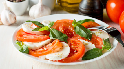 Close-up photo of caprese salad with ripe tomatoes, basil, buffalo mozzarella cheese. Italian and Mediterranean food concept. Fresh and healthy organic meal. Starter and antipasti. 