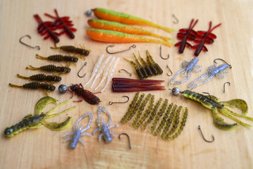 Colorful silicone fishing baits with plummets on wooden table. Various fish and worms and crayfish. Toned image and top view. Stock background, photo