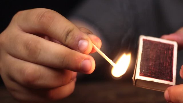 Close-up, a man takes a match out of the box and lights a match.