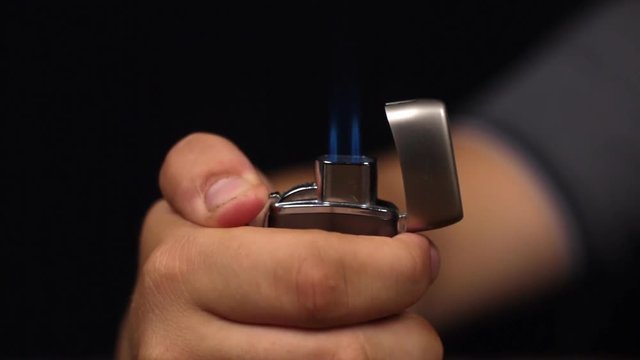 Close-up of a man ignites a gas lighter.