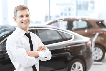 Handsome young male car salesman at car dealership