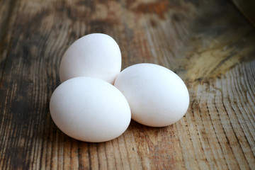 Three white eggs on wooden table
