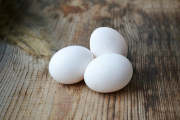 Three white eggs on wooden table