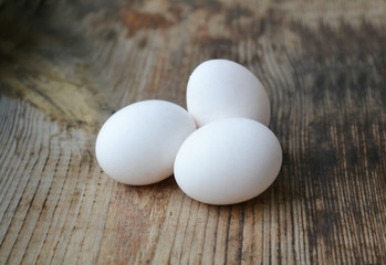 Three white eggs on wooden table