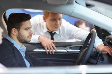 Handsome young man buying a car at the dealership