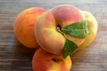Healthy and delicious peaches with green leaves on a wooden table