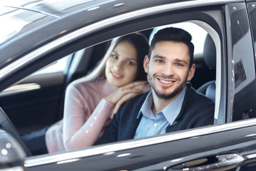 Happy loving couple choosing a car at the dealership