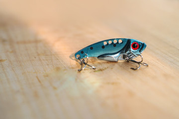 Colorful fishing baits with plummets on wooden table. Wobbler on a wooden board with beautiful eyes. Toned image and top view. Stock background, photo
