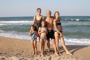 Group portrait of a healthy family of 5 people, mom, dad and three daughters on a sunny beach are...