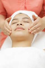 Fototapeta na wymiar Young Asian female receiving facial massage by a professional beautician