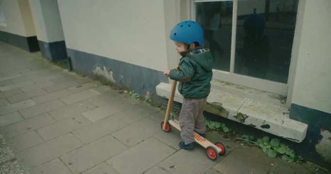 Little toddler riding a scooter on the pavement
