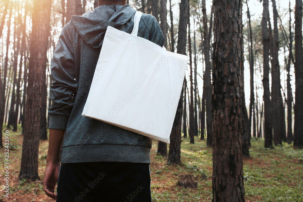 Wall mural people holding cotton bag for mockup blank in nature background