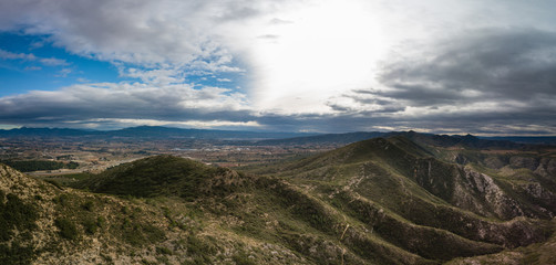 Obraz na płótnie Canvas Panoramic view of mountains with dramatic sky and small town Canals, Spain in background.