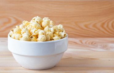 Air salty popcorn. A bowl of popcorn on a wooden table.
