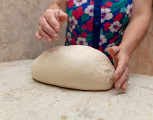 Woman kneads dough with hands in the kitchen