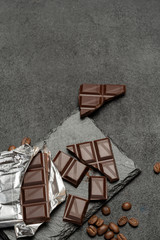 Fototapeta na wymiar dark chocolate bar and pieces on dark concrete background