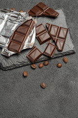dark chocolate bar and pieces on dark concrete background