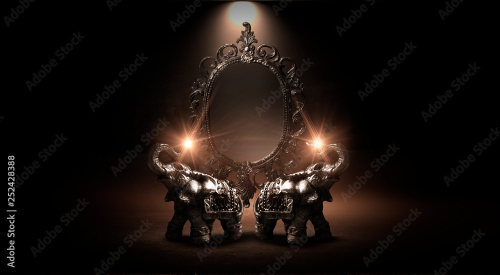 Wall mural Mirror magical, fortune telling and fulfillment of desires. Golden elephant on a wooden table. Dark room, light effect. Beautiful statuette of an elephant on the background.