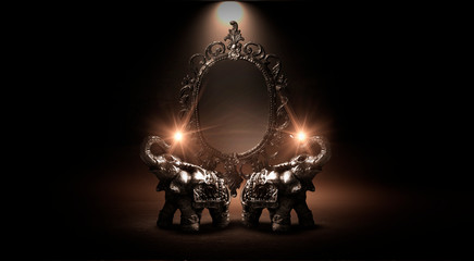 Fototapeta na wymiar Mirror magical, fortune telling and fulfillment of desires. Golden elephant on a wooden table. Dark room, light effect. Beautiful statuette of an elephant on the background.