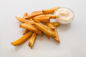 appetizing fried potato pieces with garlic and salt, with white sauce on a plate