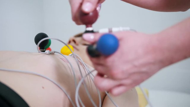 A medical clinic. A man receiving a ECG procedure. A nurse removes the vacuum suction cups