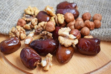 Delicious and healthy nuts and dates on burlap,on a wooden background.