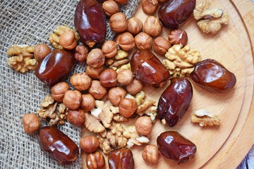 Delicious and healthy nuts and dates on burlap,on a wooden background.