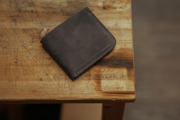Black leather wallet on wooden background. Top view. Handmade leather wallet