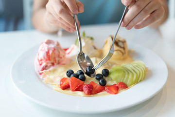 Fruity Crepe Ice Cream with scoops of  vanilla and strawberry on white plate.