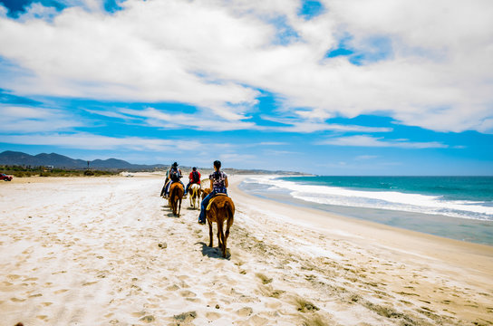 Tourists horseback riding on the beach in Cabo San Lucas, Baja California.