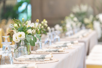Setting of tables for Wedding celebration dinner with a white bouquet and beautiful flower.
