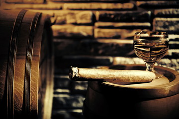 Glass of cognac and whiskey in the barrel background.Cigar.Luxury lifestyle.Wine cellar.Quality alcohol.Stone wall.Retro & Vintage style.