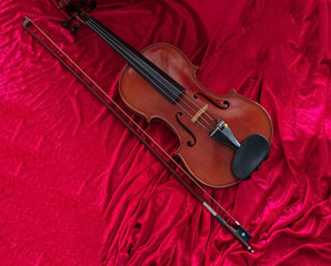 Fototapeta na wymiar The classic violin annd bow put on red cloth background,show detail of instrument