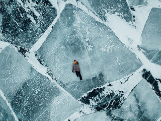 Girl walking on the ice of lake Baikal. The whole surface of the ice is cracked. Ice just got up.