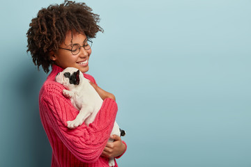 Caring affectionate lady holds puppy closely to herself, smiles gently, displays truthful feelings...