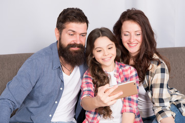Little girl use smartphone with mother and father. bearded man and woman with little girl. Mother and father make selfie for little girl. Family with little girl. Happy family at home. Filming