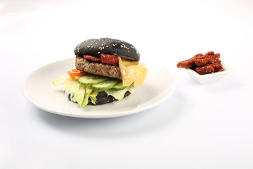 cheeseburger with black bread, beef cutlet, bacon, tomatoes and cheese slices, seasoned with sauce...
