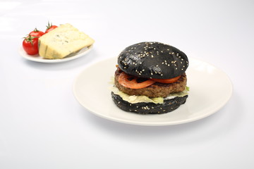 cheeseburger with black bread, beef cutlet, bacon, tomatoes and cheese slices, seasoned with sauce and green salad for a restaurant menu on a white isolated background