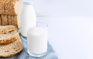 A bottle of milk and glass of milk with sliced bread on cloth indoors background for food and healthy concept. with copy space for text.