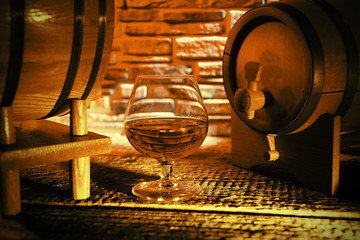 Glass of cognac and whiskey in the barrel background.Luxury lifestyle.Wine cellar.Quality alcohol.Stone wall.Retro & Vintage style.