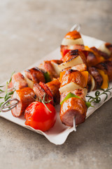 Grilled skewers with sausage, bacon and vegetables.