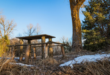 wooden table for outdoor recreation on the river bank in spring in March, waiting for visitors.