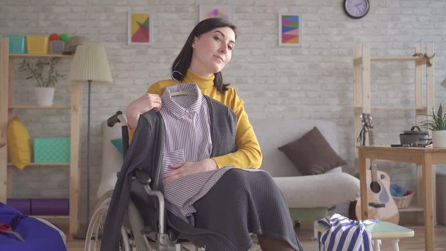 Young disabled girl in a wheelchair is going on a date trying on clothes
