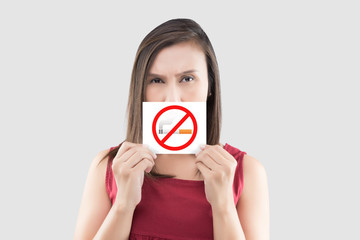 Asian woman in red blouse is holding no smoking sign on the white paper against gray background.