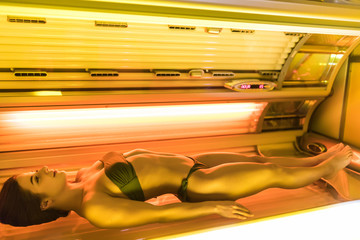 Shapely beautiful young girl sunbathing in a solarium, wants a beautiful tanned skin