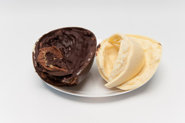Delicious homemade Easter egg, 2 flavors: coconut and truffle on a plate. Isolated on white background. Horizontal image. Split in half.