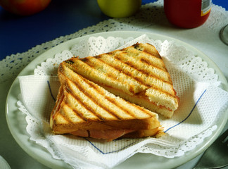 Plato con un sandwich de jamón y queso.