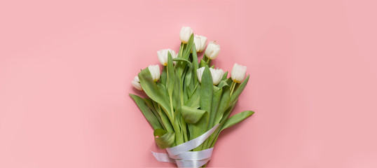 Bouquet of white tulip on millennial pink. Top view with copy space.