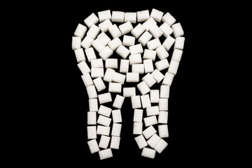 Weißer Zahn aus Würfelzucker vor schwarzem Hintergrund